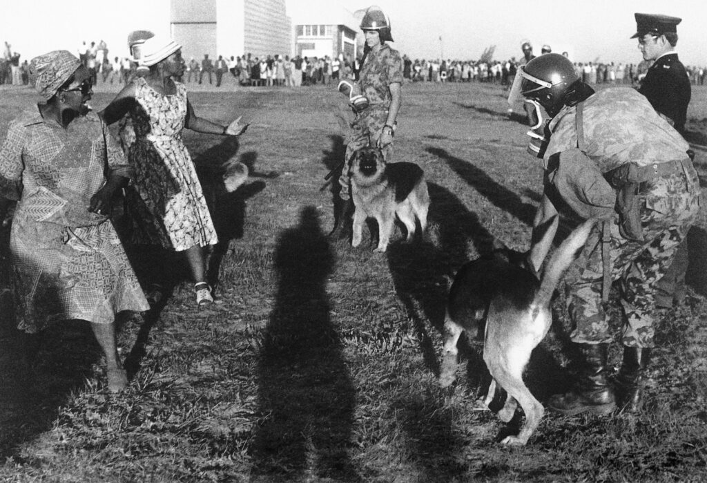 <p>Trade unionists Emma Mashinini and Joyce Piliso-Seroke face the police and their dogs in Soweto, 1980. <em>© Alf Kumalo Estate</em></p>
