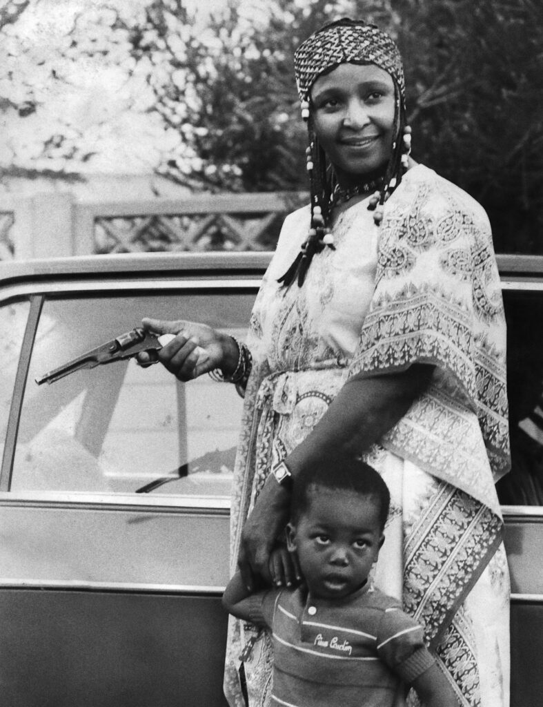<p>Winnie Mandela plays with her grandson and a toy gun in Soweto. <em>© Alf Kumalo Estate</em></p>
