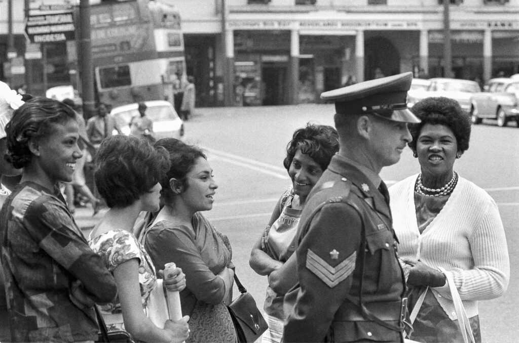 <p>Young women converse around a surly-faced policeman outside the courtroom of the Rivonia Trial. <em>© Alf Kumalo Estate</em></p>
<p>&nbsp;</p>

